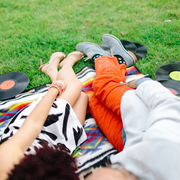 Couple lying on a blanket in the grass with LP records at their feet.